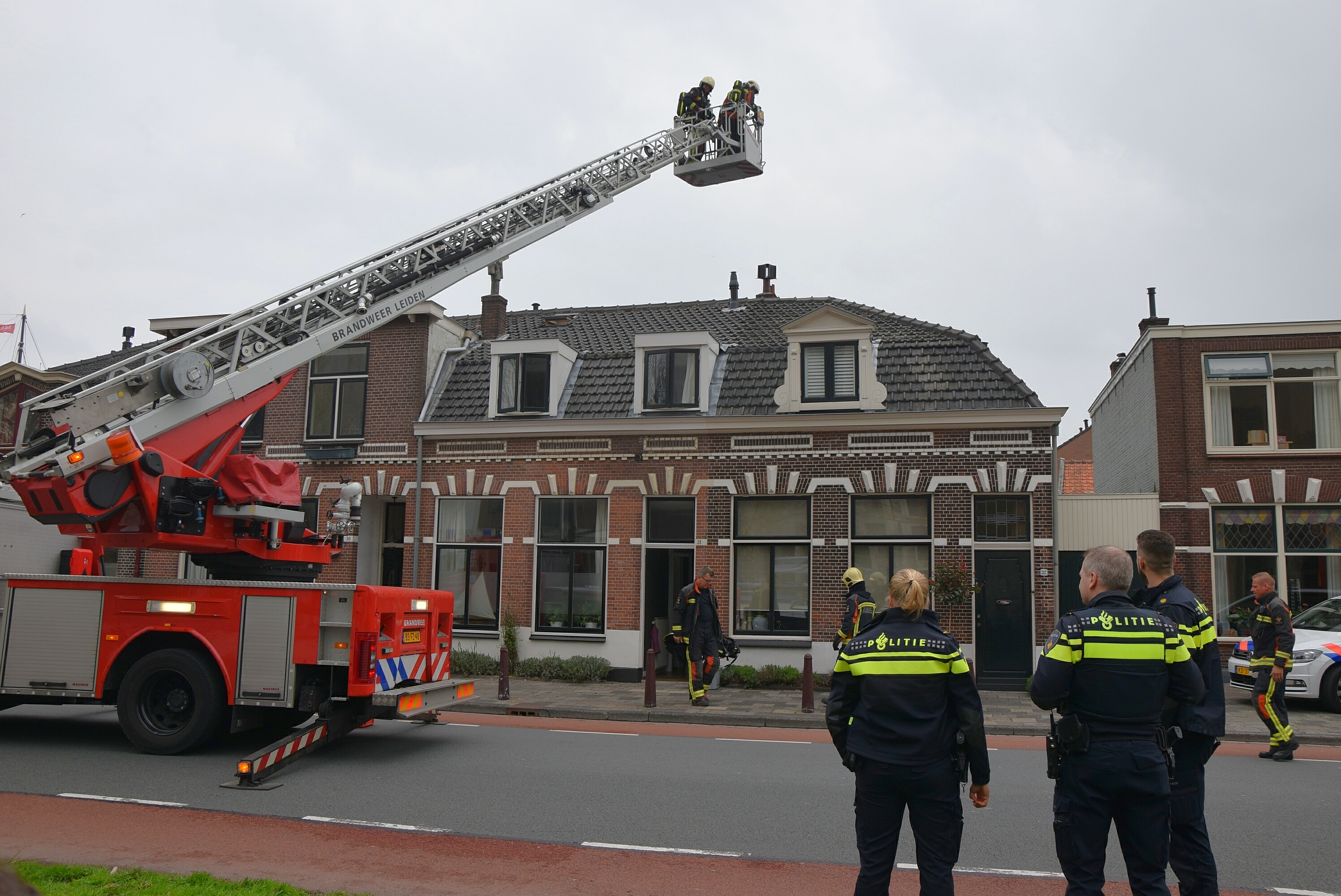 Brandweer veegt schoorsteen na brand, Zijlsingel in Leiden