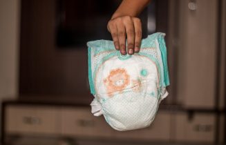 Hand holding used baby diaper